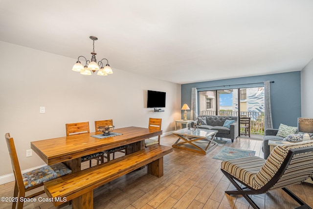 5350 Ocean Beach Blvd Unit 212, Cocoa Beach, FL 32931 - dining room featuring light wood-style flooring, a chandelier, and baseboards