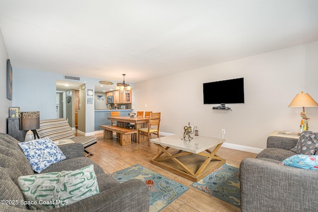 5350 Ocean Beach Blvd Unit 212, Cocoa Beach, FL 32931 - living area featuring light wood finished floors, baseboards, visible vents, and a notable chandelier
