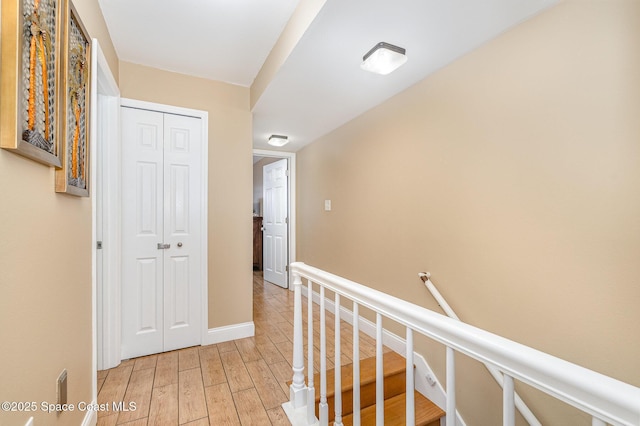 5350 Ocean Beach Blvd Unit 212, Cocoa Beach, FL 32931 - hallway featuring an upstairs landing, baseboards, and light wood-style floors