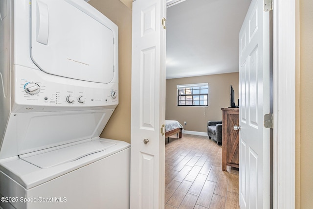 5350 Ocean Beach Blvd Unit 212, Cocoa Beach, FL 32931 - clothes washing area with light wood-style flooring, stacked washing maching and dryer, laundry area, and baseboards