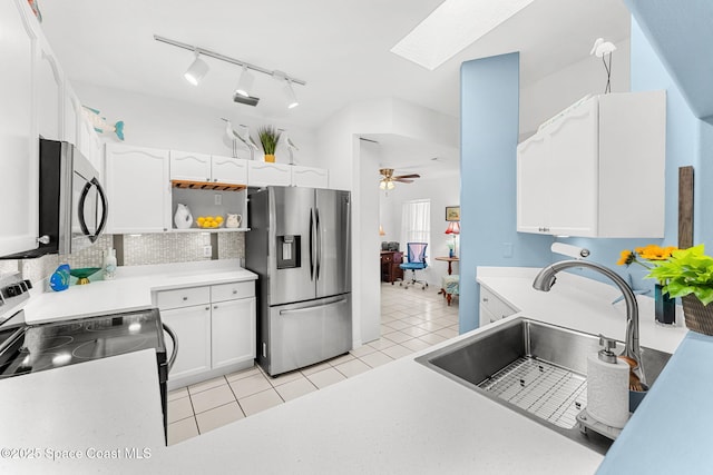 kitchen featuring a ceiling fan, a skylight, a sink, stainless steel appliances, and white cabinetry