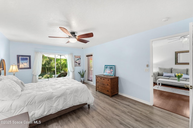 bedroom featuring access to outside, a ceiling fan, baseboards, and wood finished floors