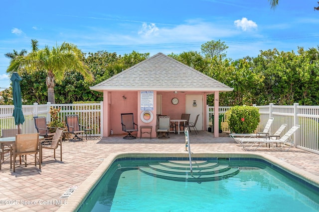 pool featuring a patio, an outdoor structure, and fence