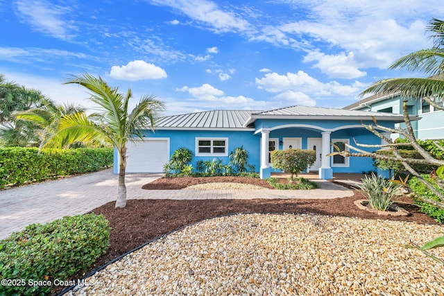 131 Harding Avenue 131& 129, Cocoa Beach, FL 32931 - view of front of house featuring stucco siding, a garage, driveway, metal roof, and a porch