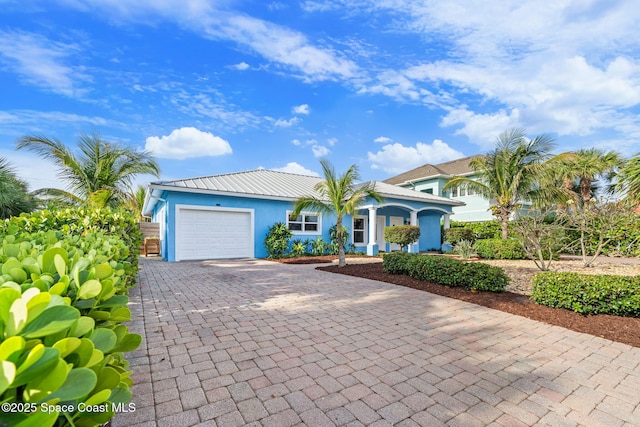 131 Harding Avenue 131& 129, Cocoa Beach, FL 32931 - view of front of home featuring decorative driveway, a garage, stucco siding, and metal roof