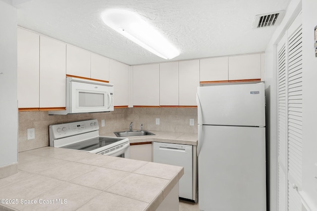 8600 Ridgewood Ave Unit 1211, Cape Canaveral, FL 32920 - kitchen with visible vents, a sink, white appliances, and tasteful backsplash