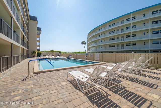community pool with fence and a patio