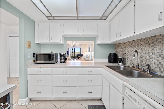 kitchen featuring light tile patterned flooring, a sink, dishwasher, stainless steel microwave, and tasteful backsplash