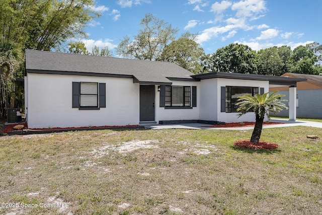 1107 Woodlawn Rd, Rockledge, FL 32955 - ranch-style house featuring a shingled roof, central AC unit, a front yard, and concrete block siding