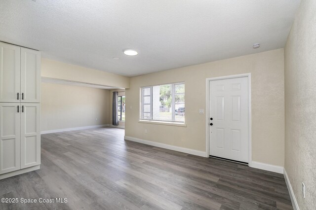 1107 Woodlawn Rd, Rockledge, FL 32955 - unfurnished living room featuring dark wood-style flooring, a textured ceiling, and baseboards