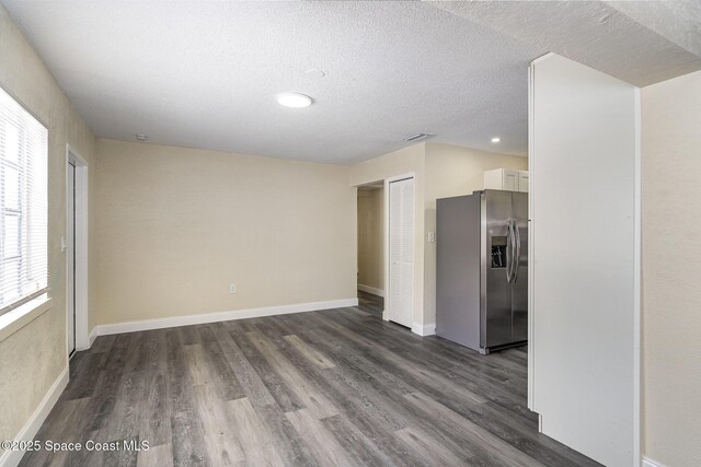 1107 Woodlawn Rd, Rockledge, FL 32955 - unfurnished living room with a textured ceiling, dark wood-style flooring, baseboards, and visible vents