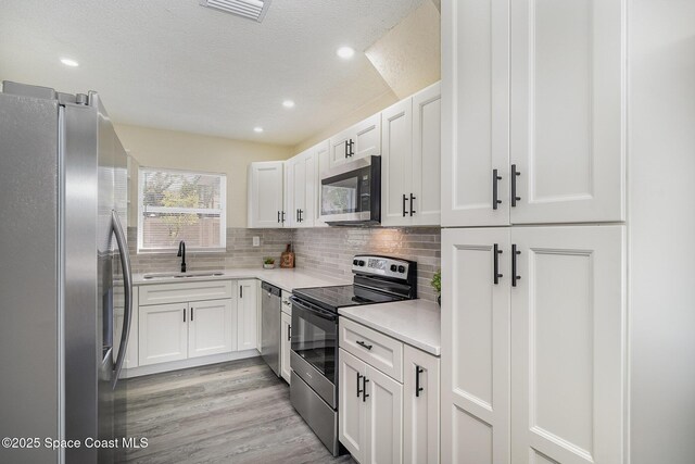1107 Woodlawn Rd, Rockledge, FL 32955 - kitchen with a sink, stainless steel appliances, tasteful backsplash, light countertops, and white cabinets