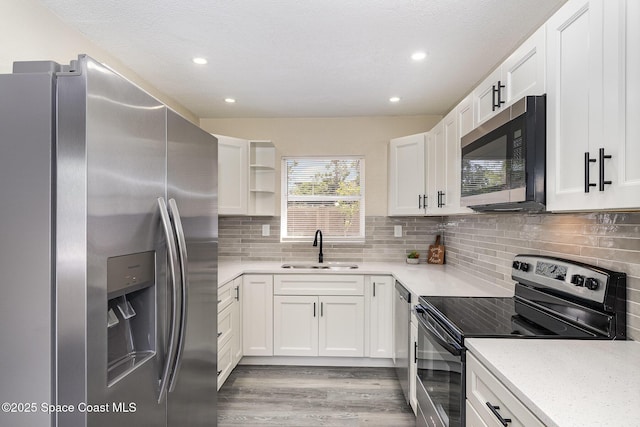 1107 Woodlawn Rd, Rockledge, FL 32955 - kitchen with open shelves, white cabinets, light wood-style flooring, a sink, and stainless steel appliances