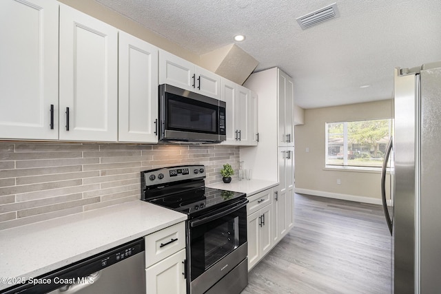 1107 Woodlawn Rd, Rockledge, FL 32955 - kitchen with stainless steel appliances, light wood-style floors, tasteful backsplash, visible vents, and white cabinets