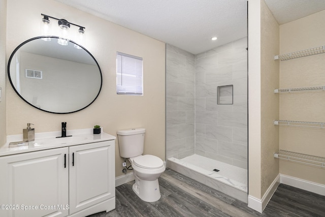 1107 Woodlawn Rd, Rockledge, FL 32955 - full bath with a textured ceiling, a tile shower, visible vents, toilet, and wood finished floors