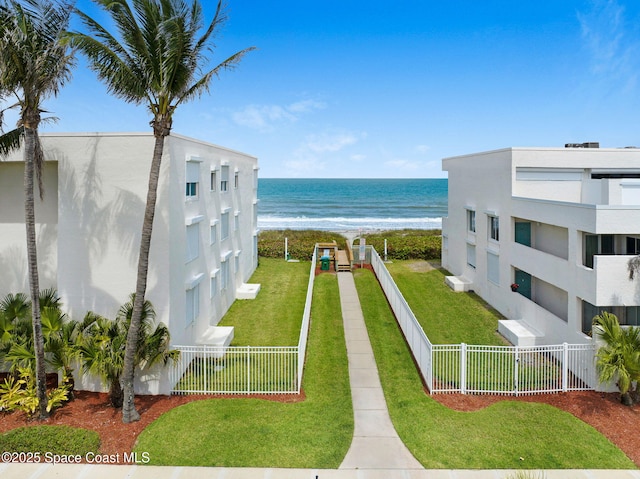 view of property's community with a beach view, a yard, a water view, and fence