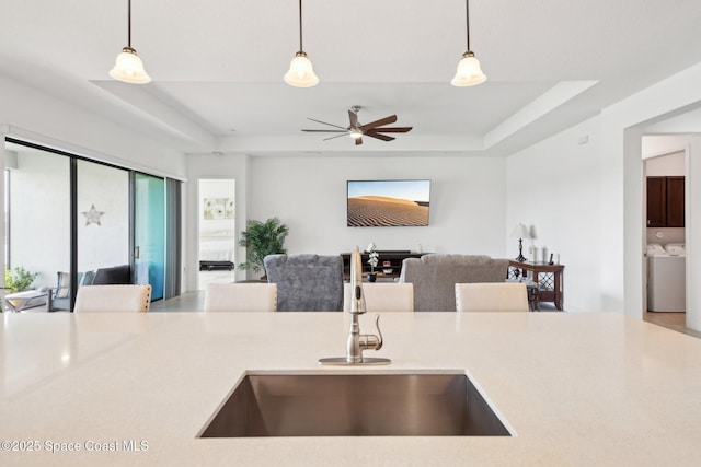 2241 Caravan Pl, Melbourne, FL 32940 - kitchen featuring a sink, open floor plan, a tray ceiling, and hanging light fixtures