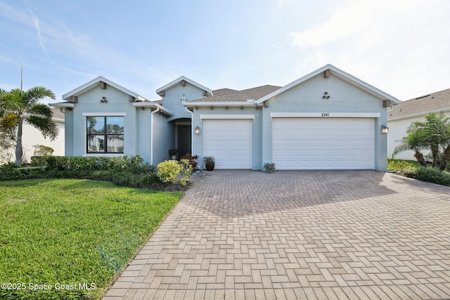 2241 Caravan Pl, Melbourne, FL 32940 - view of front facade with decorative driveway, stucco siding, an attached garage, and a front lawn