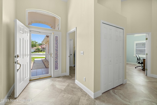 entryway with light tile patterned floors, baseboards, and a high ceiling