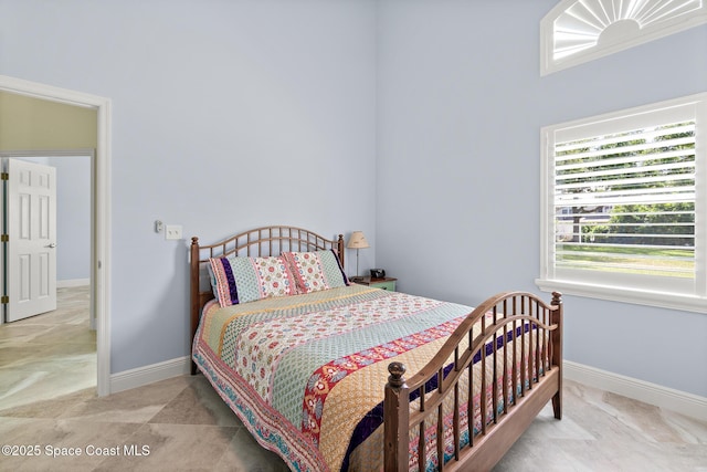 bedroom with a high ceiling and baseboards