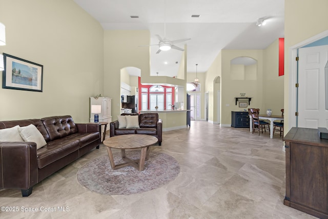 living room with arched walkways, high vaulted ceiling, a ceiling fan, and baseboards