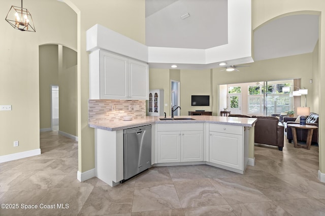 kitchen with a sink, a peninsula, stainless steel dishwasher, arched walkways, and open floor plan