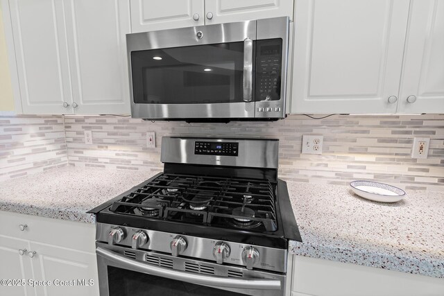 kitchen featuring tasteful backsplash, stainless steel appliances, white cabinets, and light stone counters