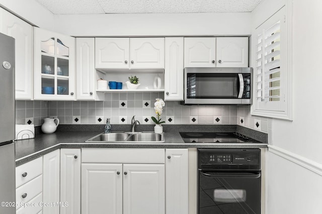 kitchen featuring stainless steel appliances, a sink, dark countertops, white cabinetry, and decorative backsplash