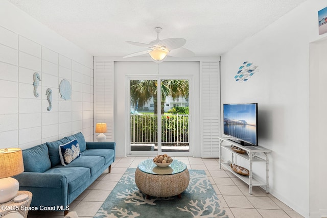 living room with light tile patterned flooring, a ceiling fan, tile walls, and a textured ceiling