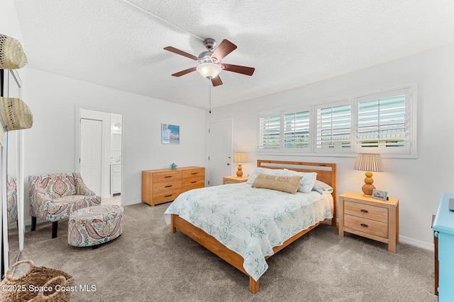 carpeted bedroom with a textured ceiling, a ceiling fan, baseboards, and ensuite bathroom