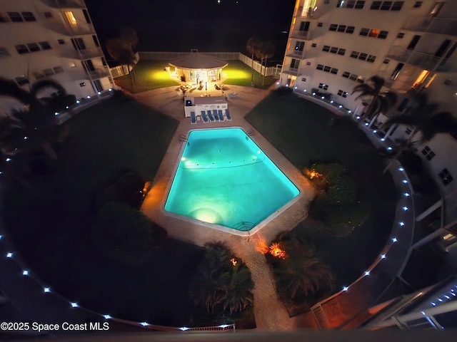 pool at night with a patio and a community pool