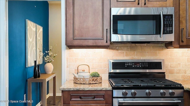 117 Windward Way, Indian Harbour Beach, FL 32937 - kitchen with light stone countertops, decorative backsplash, dark brown cabinetry, baseboards, and appliances with stainless steel finishes
