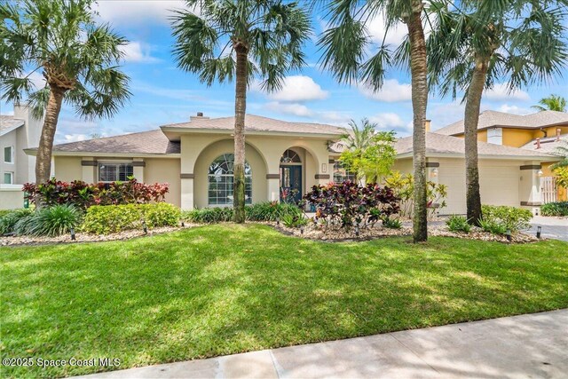 117 Windward Way, Indian Harbour Beach, FL 32937 - view of front of house with stucco siding, concrete driveway, a front lawn, and a garage