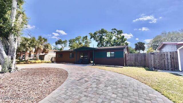 view of front of home with fence, a front yard, and curved driveway