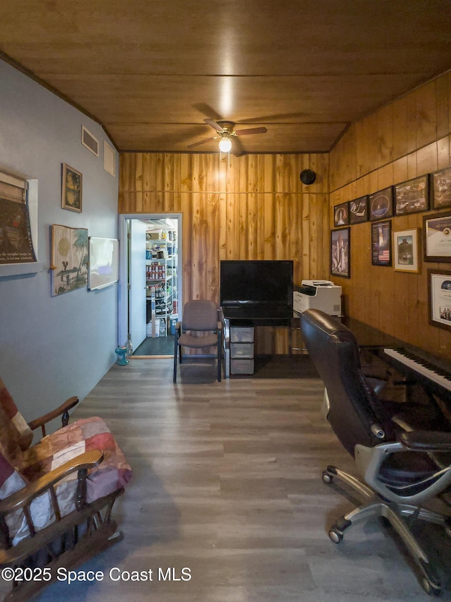 office featuring wooden ceiling, wood walls, a ceiling fan, and visible vents