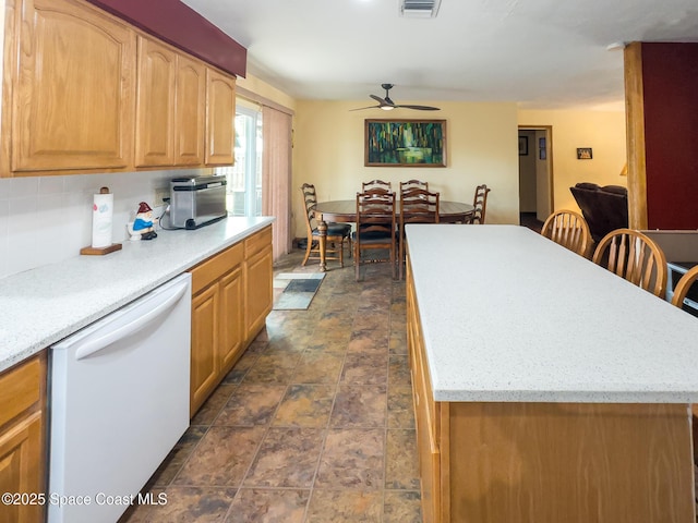 kitchen featuring visible vents, stone finish floor, ceiling fan, dishwasher, and a kitchen island