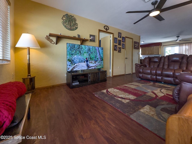 living area featuring baseboards, a ceiling fan, and wood finished floors