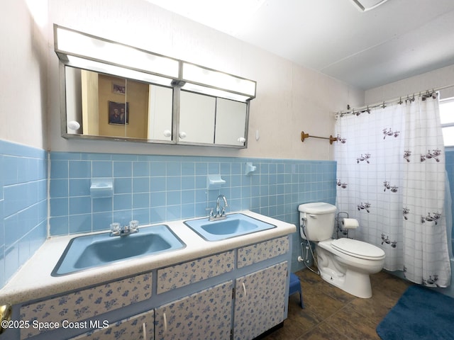 bathroom with toilet, a sink, curtained shower, and tile walls