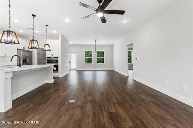 unfurnished living room with a sink, dark wood-type flooring, and recessed lighting