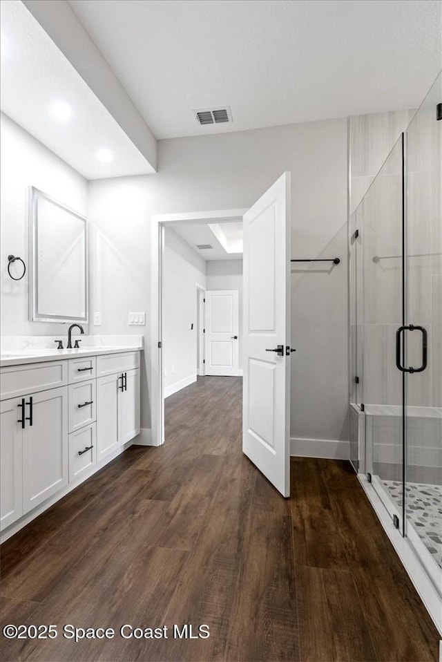 bathroom with a stall shower, baseboards, visible vents, wood finished floors, and vanity