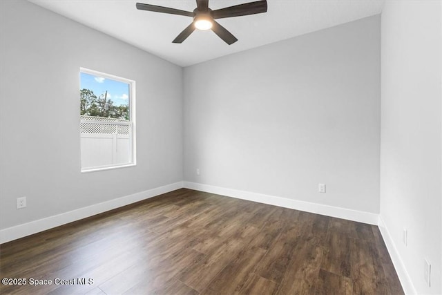 spare room with dark wood finished floors, ceiling fan, and baseboards