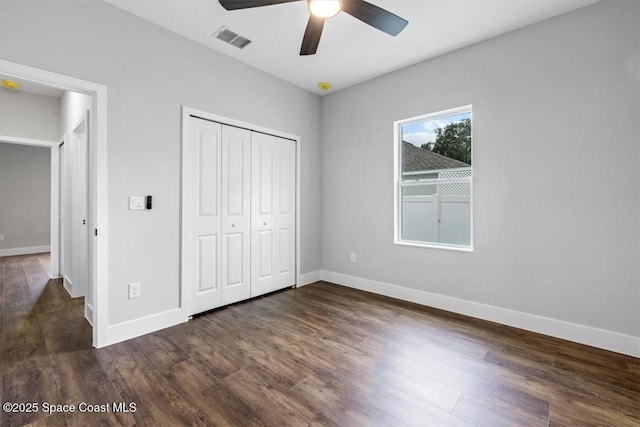 unfurnished bedroom featuring dark wood-type flooring, a closet, visible vents, and baseboards
