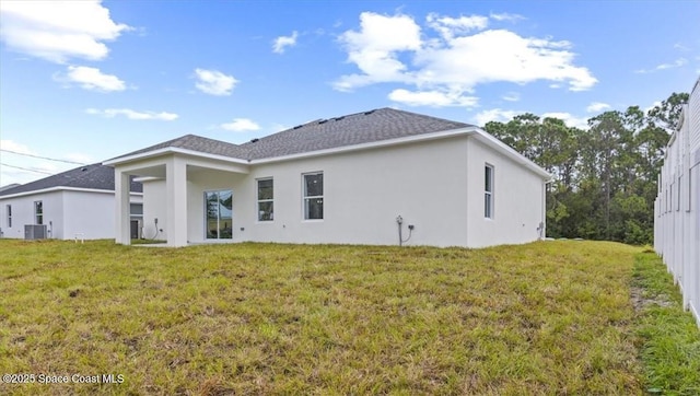 rear view of property with stucco siding, a shingled roof, and a lawn