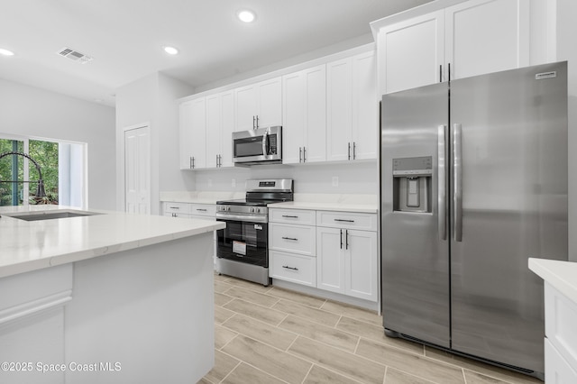 8276 100th Ave, Vero Beach, FL 32967 - kitchen featuring stainless steel appliances, recessed lighting, white cabinetry, light stone countertops, and light wood finished floors