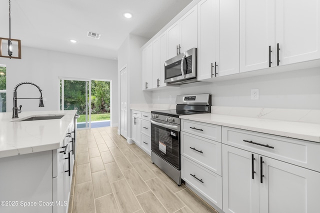8276 100th Ave, Vero Beach, FL 32967 - kitchen with appliances with stainless steel finishes, recessed lighting, white cabinets, decorative light fixtures, and light stone countertops