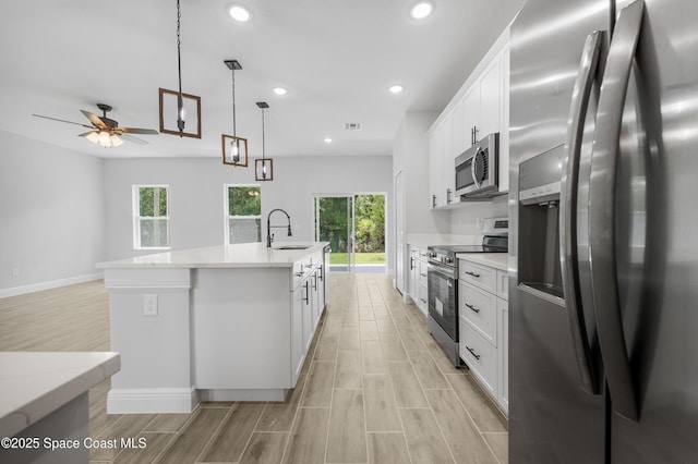 8276 100th Ave, Vero Beach, FL 32967 - kitchen featuring appliances with stainless steel finishes, a ceiling fan, recessed lighting, a kitchen island with sink, and light wood-style flooring