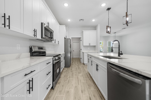 8276 100th Ave, Vero Beach, FL 32967 - kitchen with appliances with stainless steel finishes, recessed lighting, white cabinetry, hanging light fixtures, and light stone counters