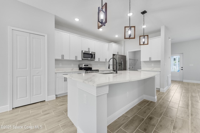 8276 100th Ave, Vero Beach, FL 32967 - kitchen with appliances with stainless steel finishes, wood tiled floors, a center island with sink, white cabinets, and recessed lighting