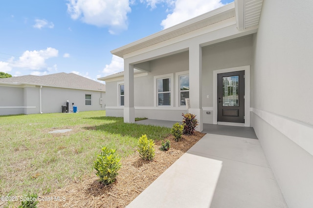 8276 100th Ave, Vero Beach, FL 32967 - view of exterior entry featuring stucco siding and a lawn