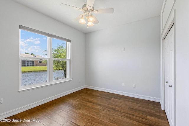 4117 Melrose Ct, Melbourne, FL 32940 - empty room featuring a ceiling fan, a water view, baseboards, and dark wood-type flooring